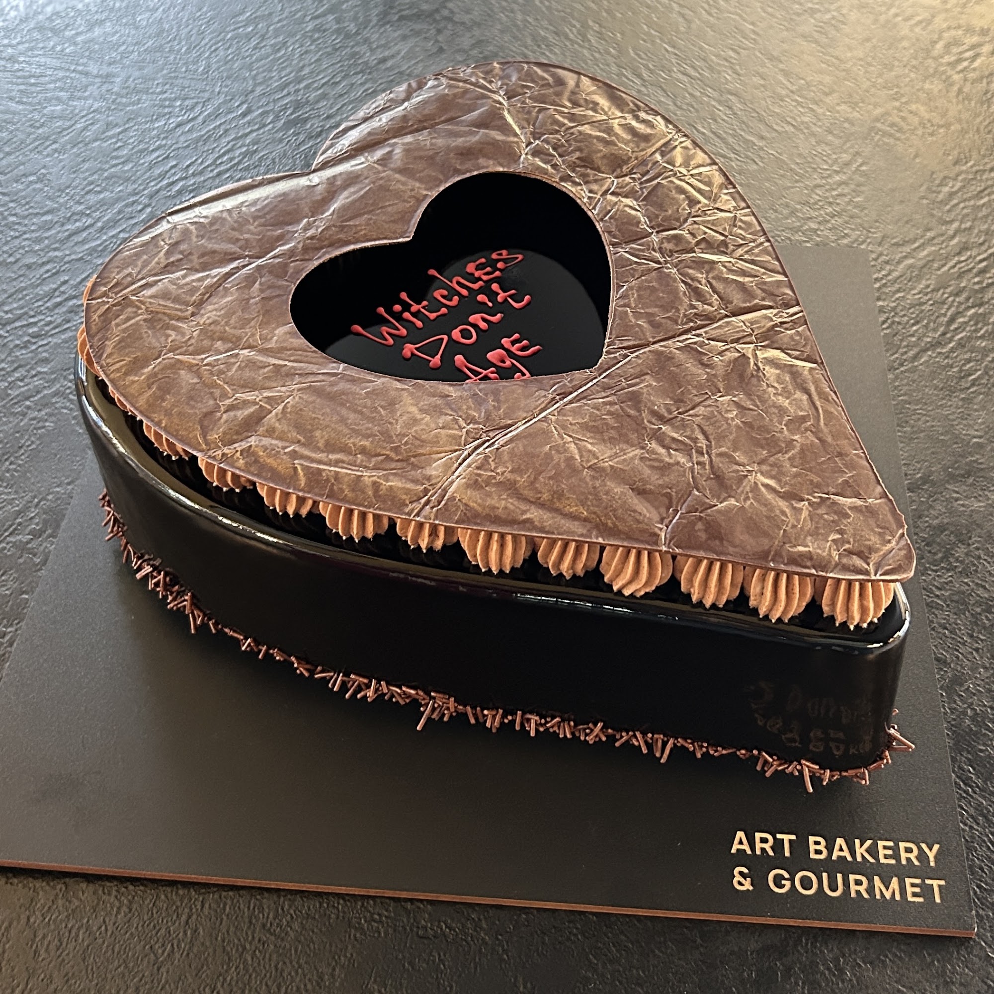 Heart-shaped black chocolate celebration cake with bronze chocolate decoration