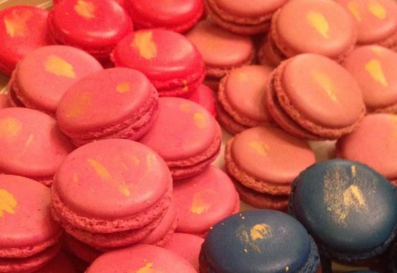 Assorted coral, pink and blue macarons with delicate gold brushstrokes