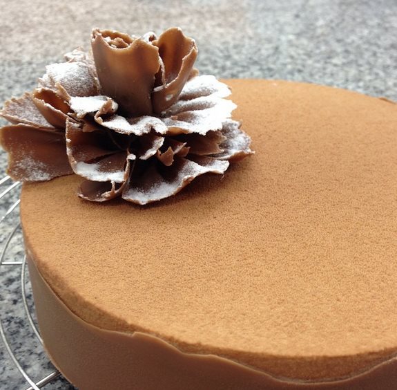 Minimalist cocoa cake decorated with a large handmade chocolate flower