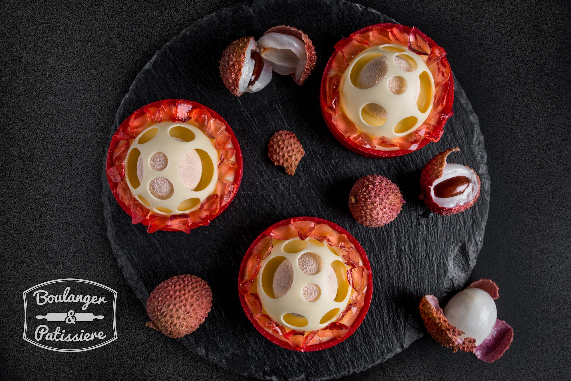 Red lychee tartlets with white chocolate domes and translucent fruit decoration