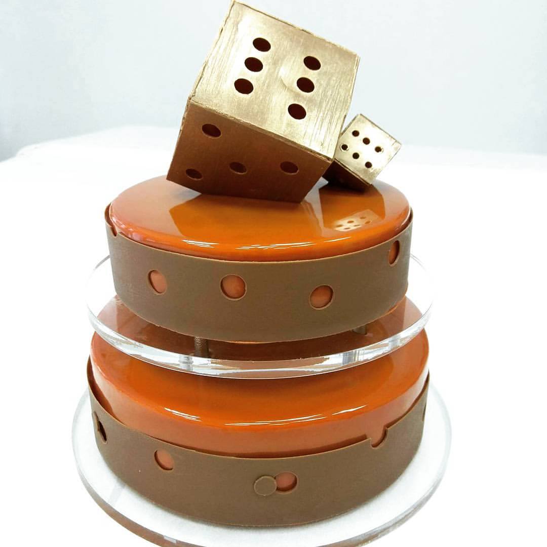 Two-tier caramel cake decorated with large metallic chocolate dice