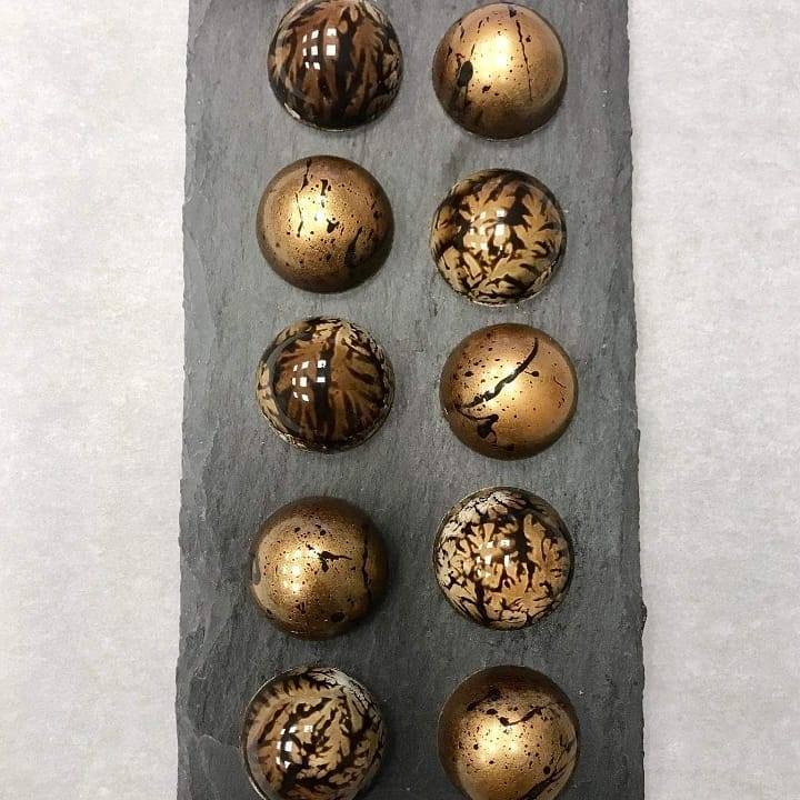 Bronze and marbled artisan chocolate bonbons arranged on black slate