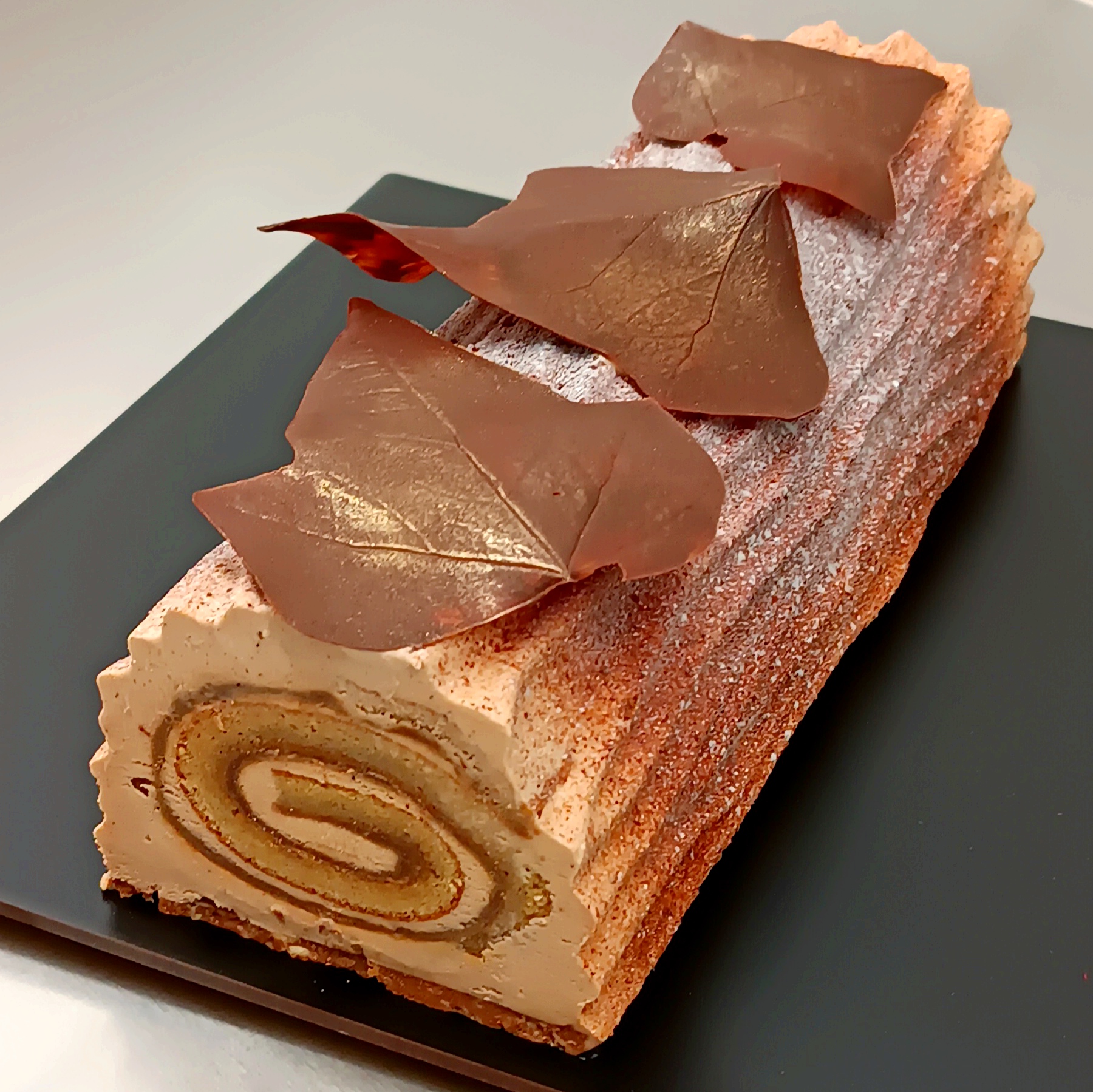 Rectangular log cake with layered structure and sculptural chocolate decoration