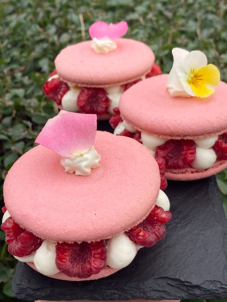 Pink macarons with fresh raspberries, vanilla cream and edible flowers