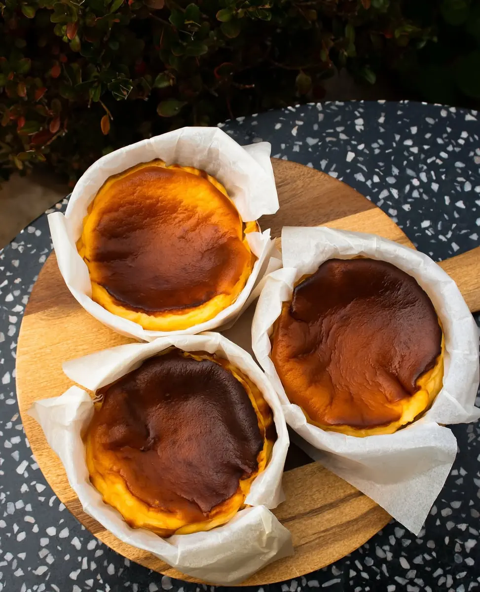 Three individual Basque cheesecakes with dark caramelised tops in parchment