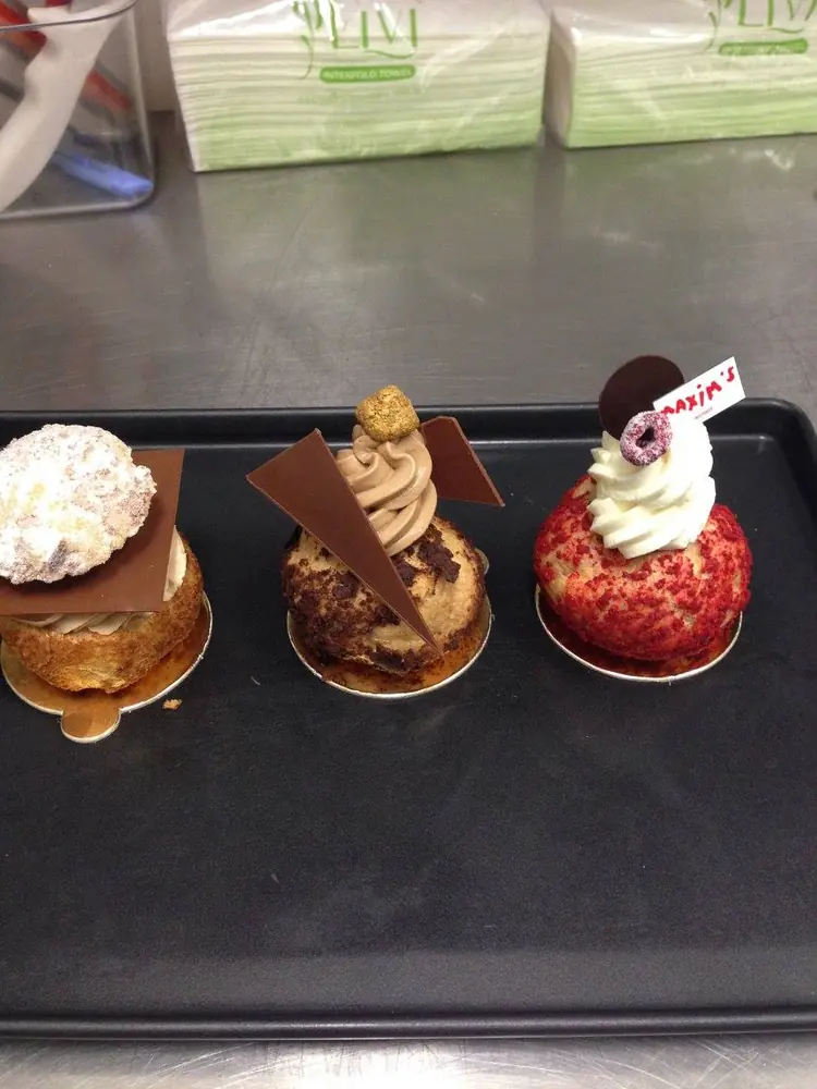 Three decorated choux pastries with cream, chocolate and berry finishes