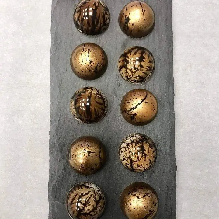 Assorted glossy moulded chocolate bonbons with bronze and marbled finishes