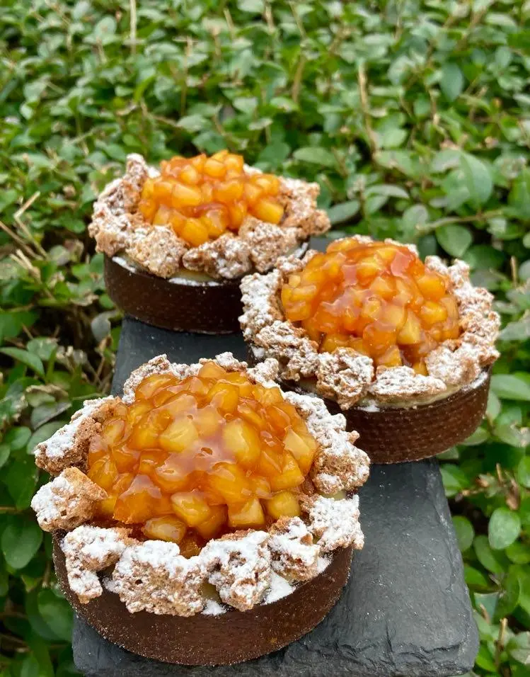 Individual French fruit tartlets with crisp shells, piped cream and fresh fruit