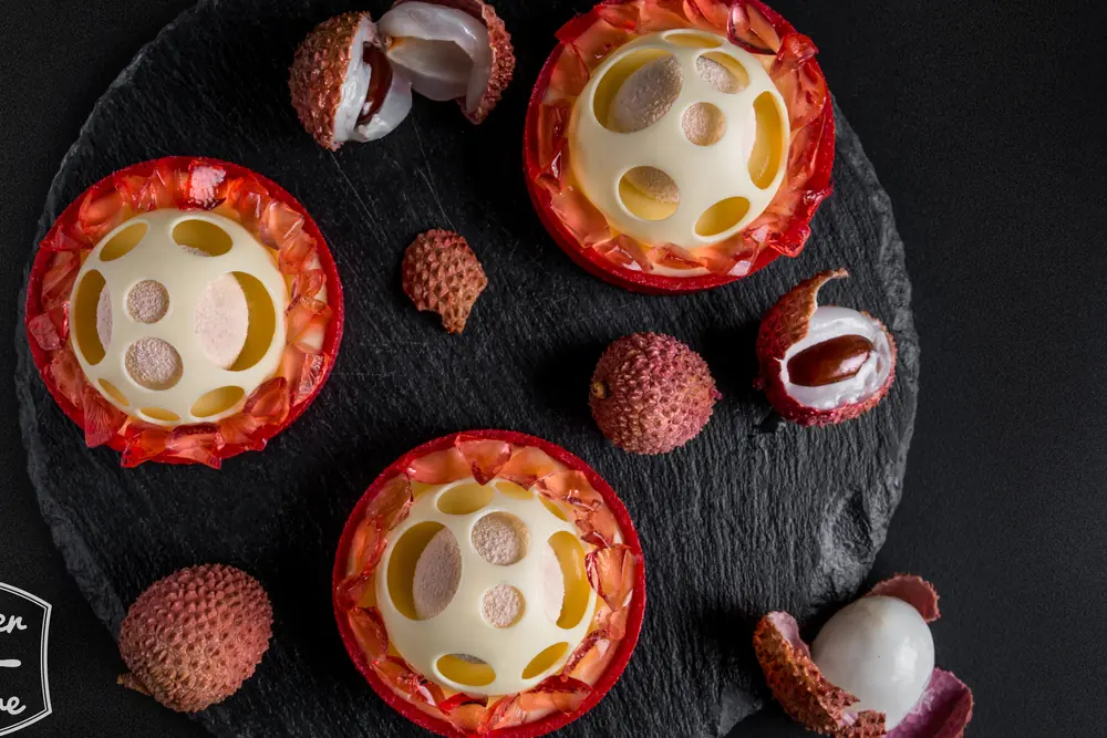 Lychee-led red tartlets with translucent fruit decoration and white chocolate domes