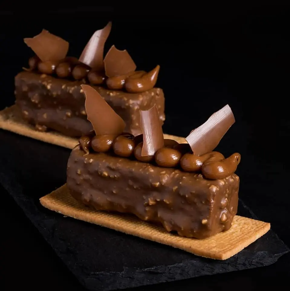 Rectangular chocolate pastries with textured nut coating and piped chocolate cream