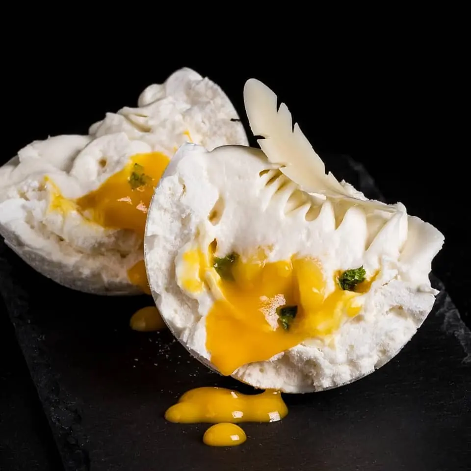 Crisp white meringue dessert opened to reveal a soft centre and bright fruit filling